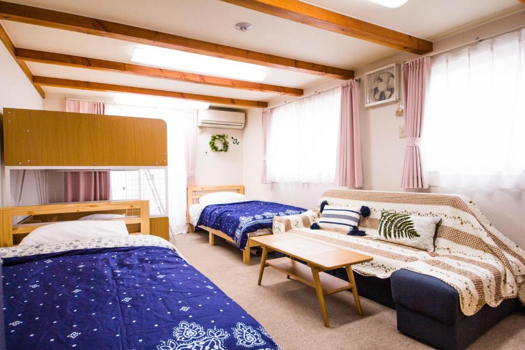 um quarto com duas camas, um sofá e uma mesa em The Familiar Inn ー 旅館ホテル業 em Osaka