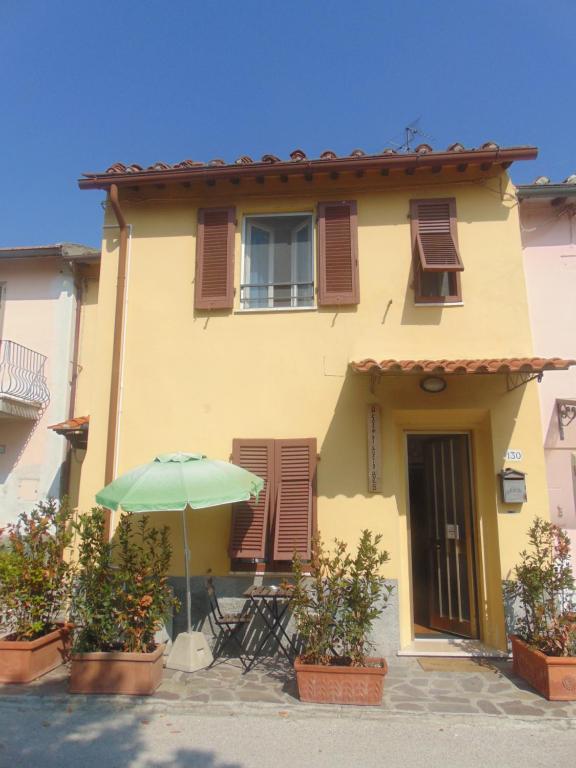 a house with a table and an umbrella in front of it at A Casa di Lucia in Pisa