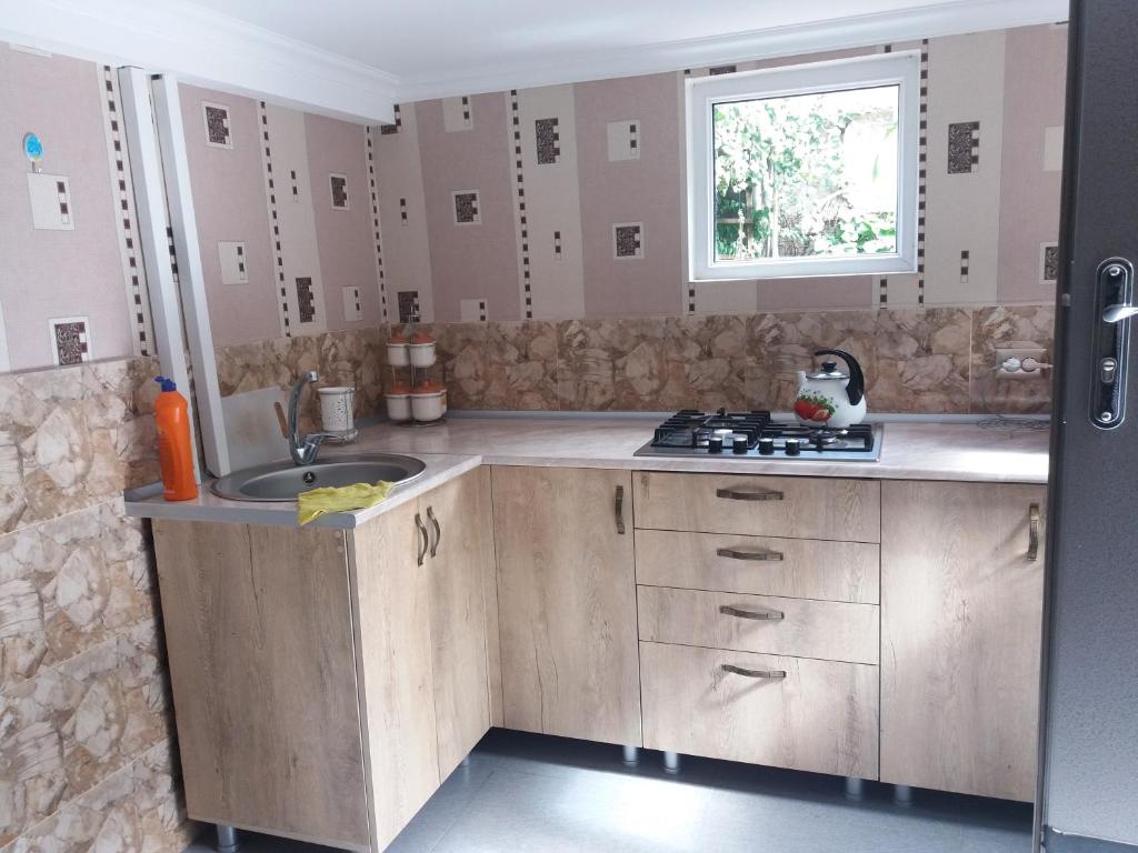 eine Küche mit Holzschränken, einem Waschbecken und einem Fenster in der Unterkunft House Rustaveli street 112 in Achalziche