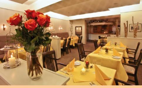 a restaurant with tables with red roses in a vase at Hotel Rosenflora in Nideggen
