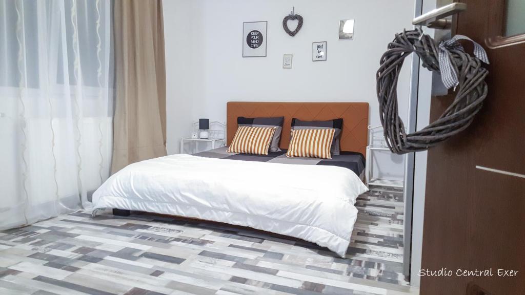 Schlafzimmer mit einem Bett mit weißer Bettwäsche und Kissen in der Unterkunft Studio Central Exer II in Bukarest