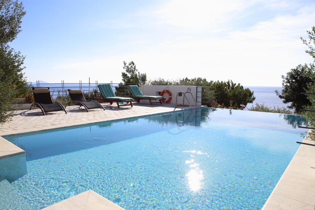 basen z krzesłami i ocean w tle w obiekcie Euphoria - South Crete Villas w mieście Achlia