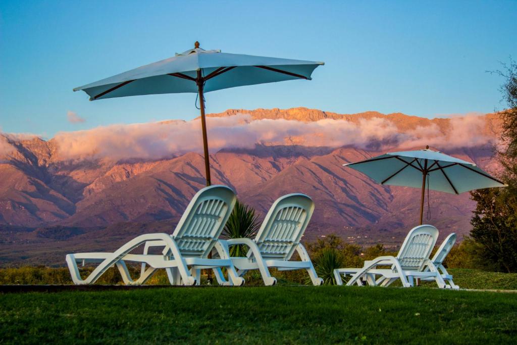 three chairs and an umbrella with mountains in the background at Zahrek Resorts & SPA in San Javier