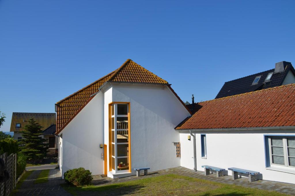 une maison blanche avec une porte et des bancs en bois dans l'établissement Haus Vineta, à Thiessow