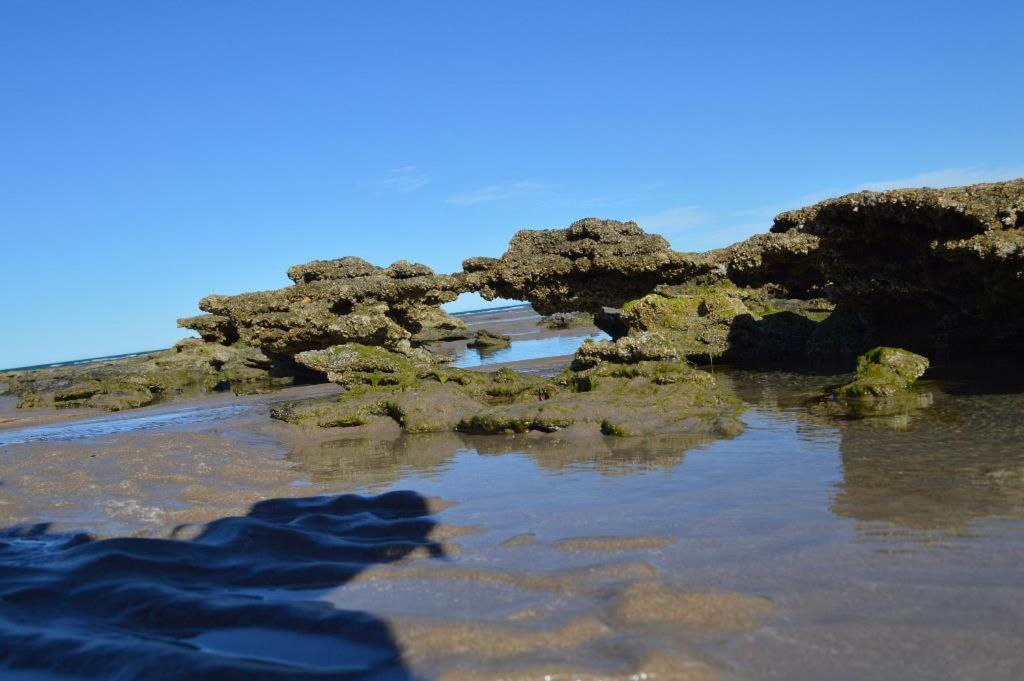 un grupo de rocas en el agua en una playa en Mecohue en Playas Doradas