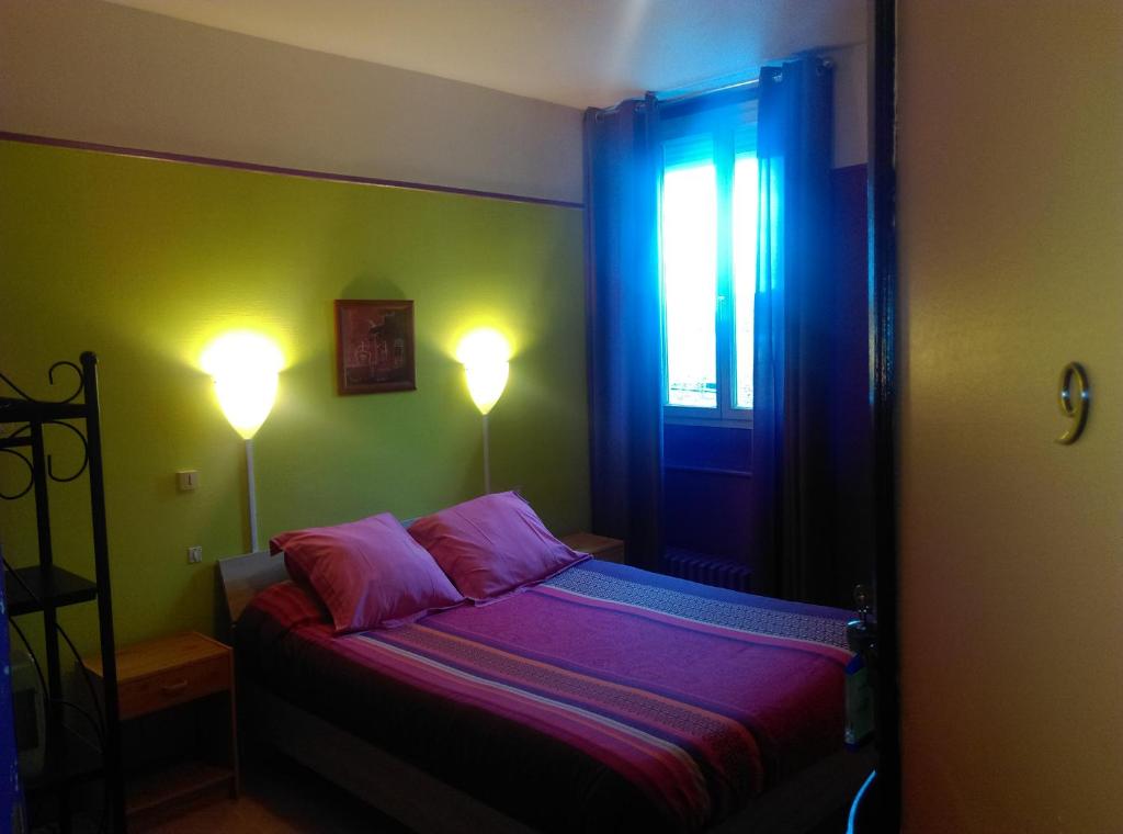 una camera da letto con un letto con due lampade e una finestra di Hotel le Rallye a Soissons