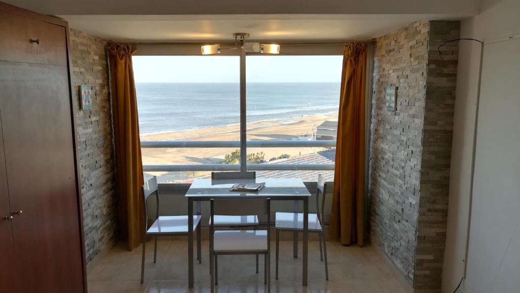 comedor con mesa y sillas y ventana grande en el Departamento Villa Gesell Sur Sobre Playa y 140 Vista al Mar en Villa Gesell