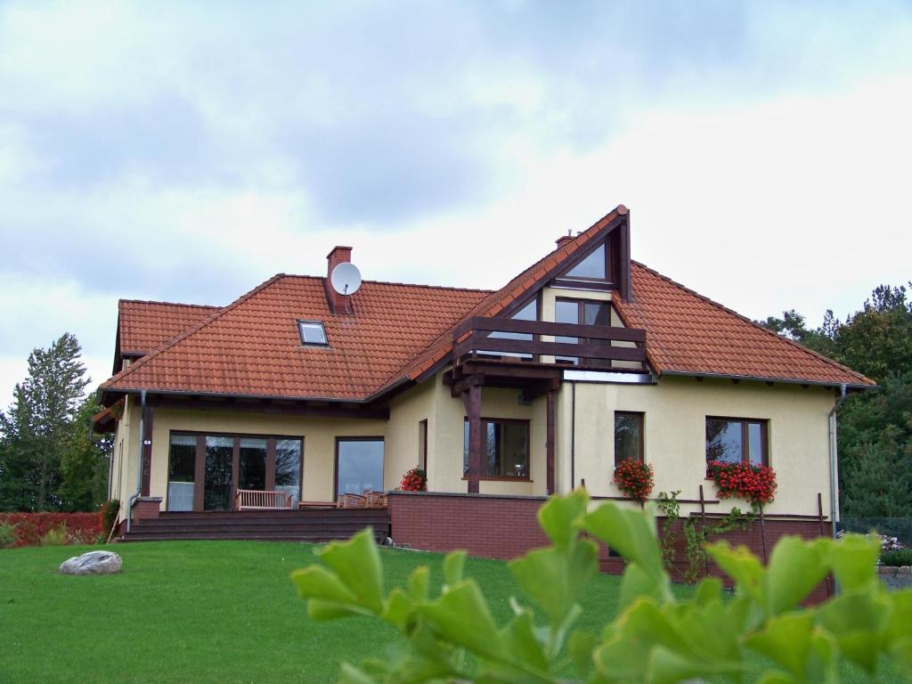 a house with a red roof on a green field at DW Złote Kłosy in Wrony