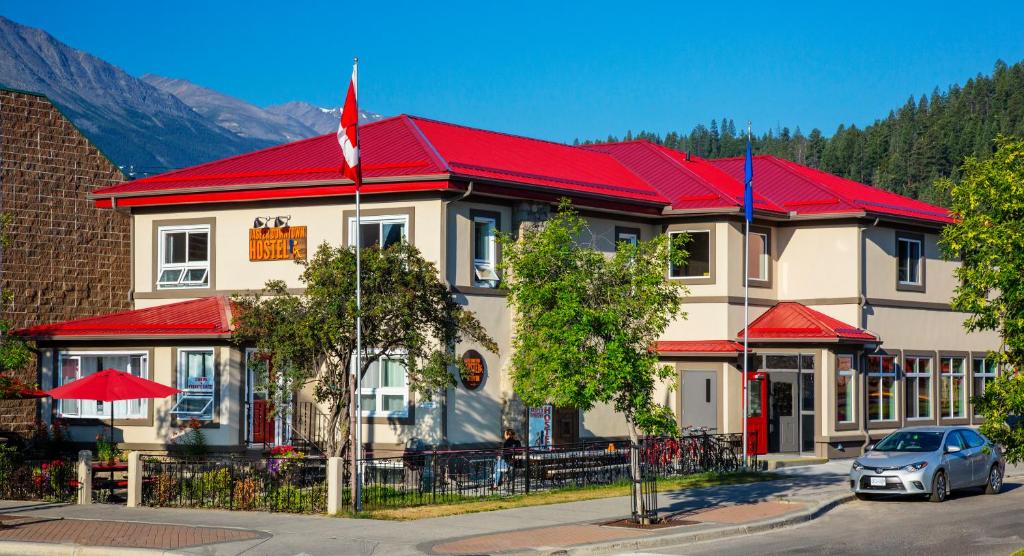 a building with a red roof with a car parked in front at Jasper Downtown Hostel in Jasper