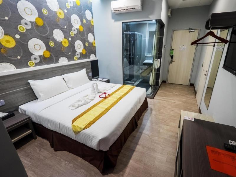 1 dormitorio con 1 cama grande con manta amarilla en Indra Hotel Ipoh, en Ipoh