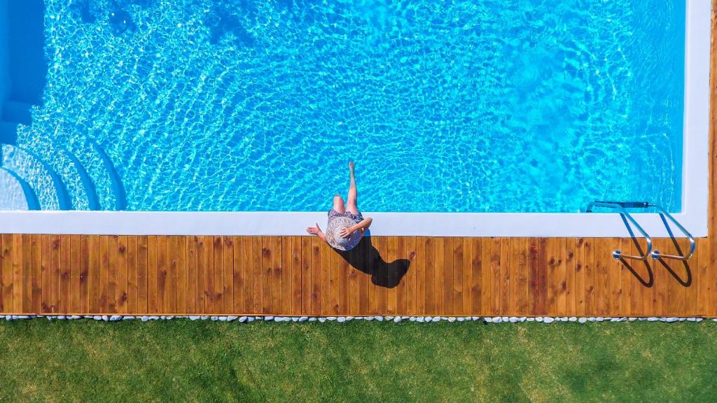 a person laying on the edge of a swimming pool at Iro Suites in Andros