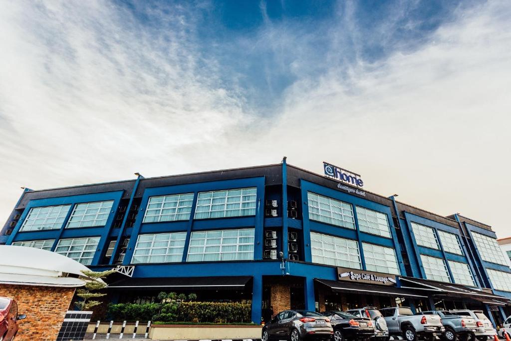 a blue building with cars parked in a parking lot at Athome Boutique Hotel in Bintulu