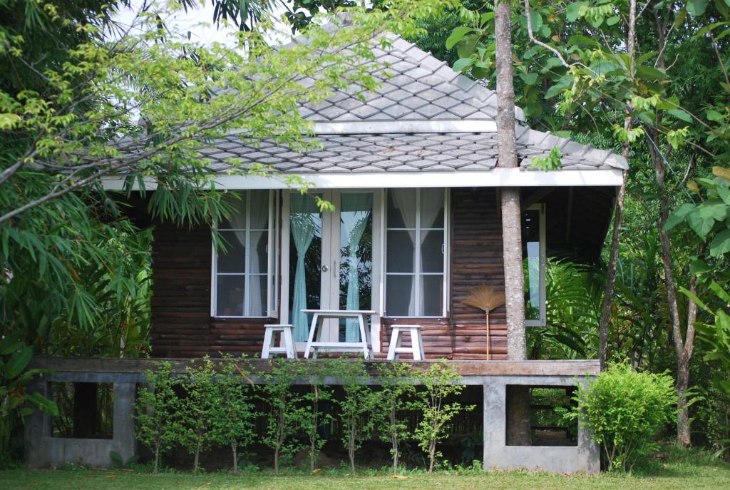 ein kleines Haus mit zwei Stühlen auf der Veranda in der Unterkunft BanJankapor in Kaeng Kachan