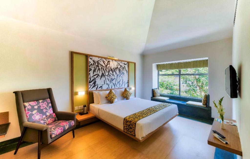 a bedroom with a bed and a chair and a window at Sterling Wayanad in Sultan Bathery