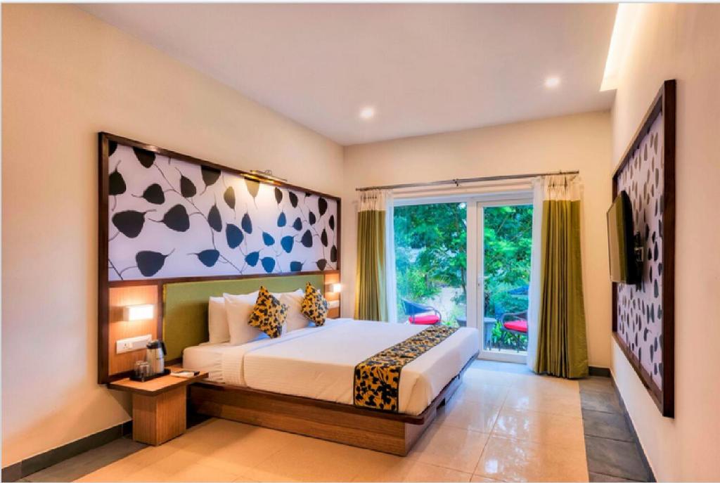 a bedroom with a bed and a large window at Sterling Wayanad in Sultan Bathery