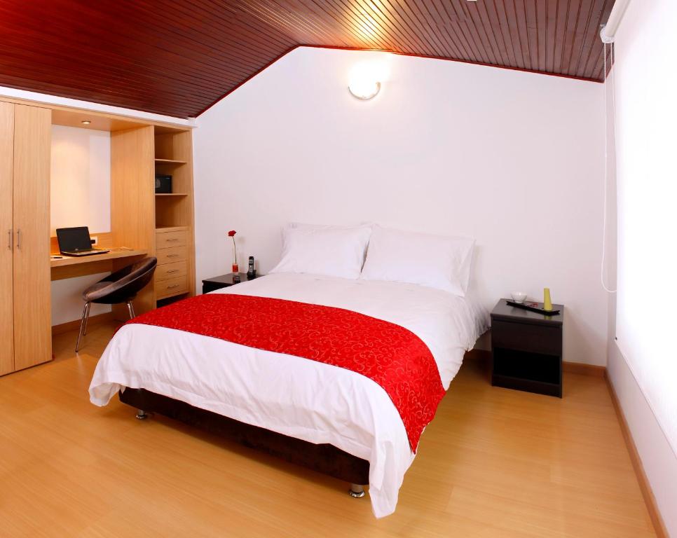 a bedroom with a large bed with a red blanket at Hotel TuKasa Inn in Bogotá