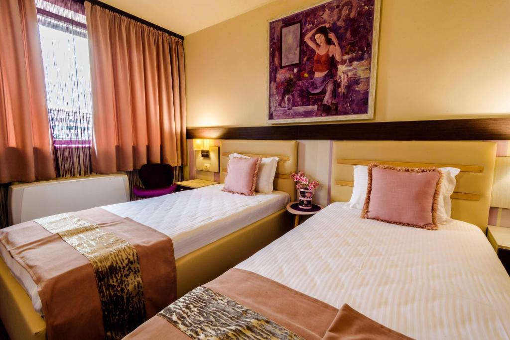 a hotel room with two beds and a painting on the wall at Hotel Rostov in Pleven