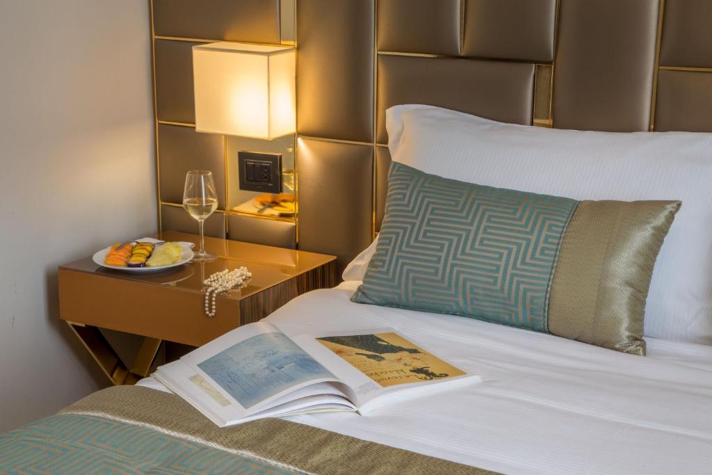 książka na łóżku z talerzem jedzenia i kieliszkiem wina w obiekcie Hotel Gioberti w Rzymie