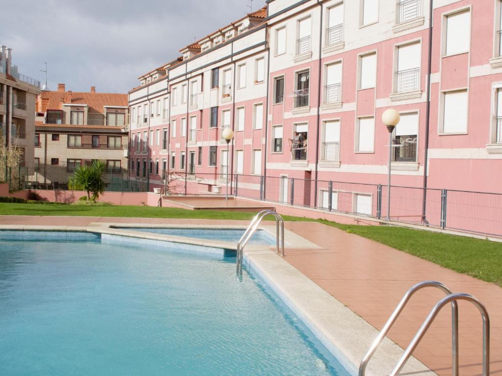 a swimming pool in front of some buildings at Desconectaengalicia La Perla, piscina y parking in Sanxenxo