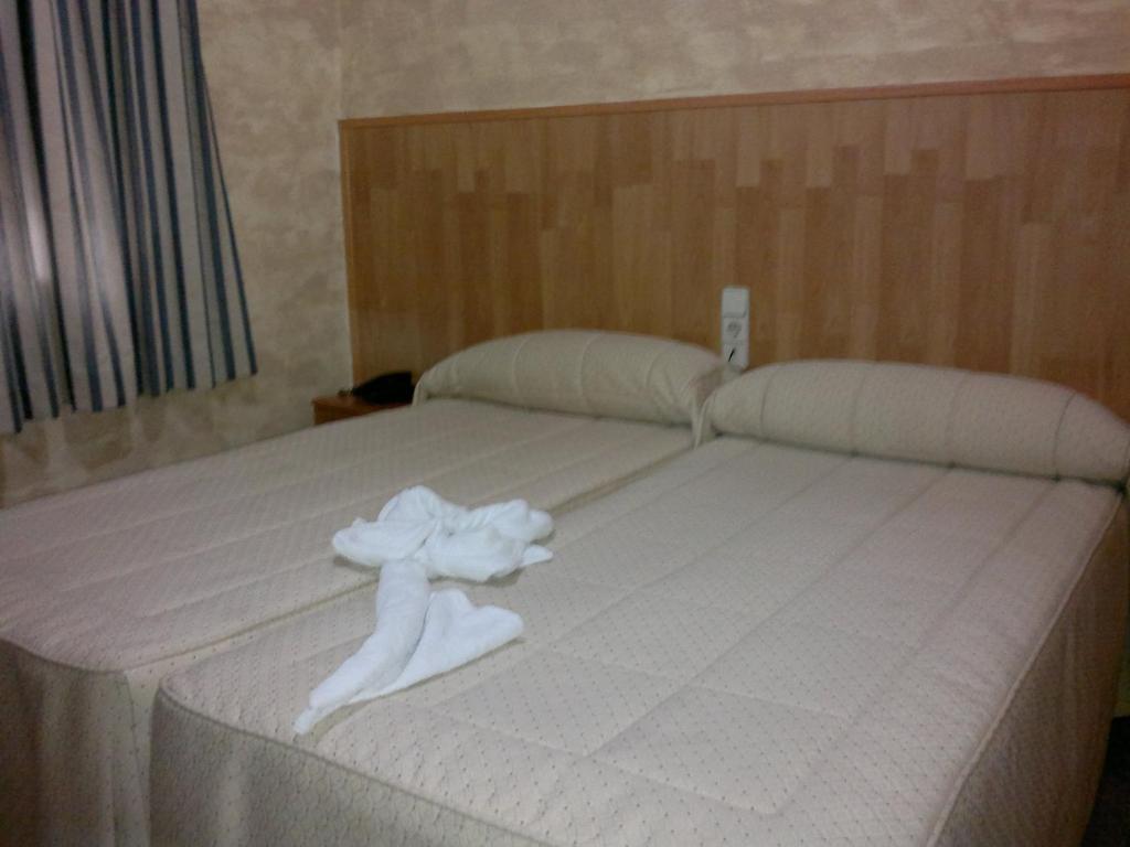 Una cama con un montón de toallas blancas. en Hostal Mays en Numancia de la Sagra