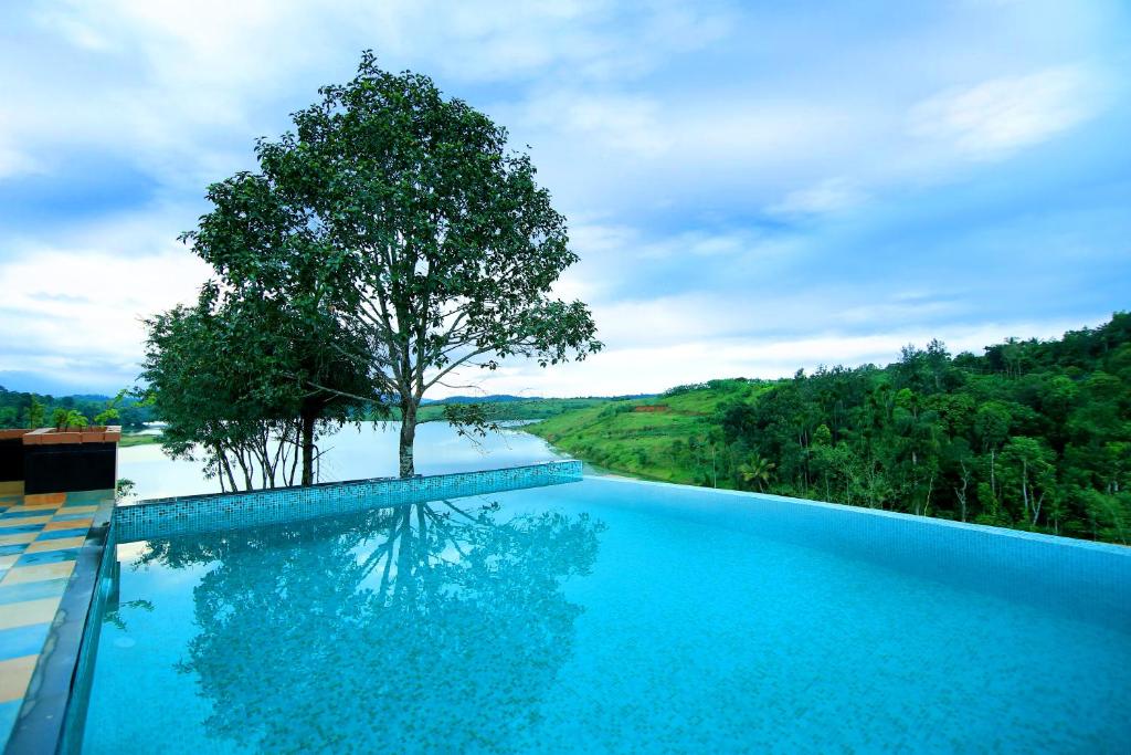 een zwembad met een boom naast een rivier bij Vista Del Lago in Ambalavayal