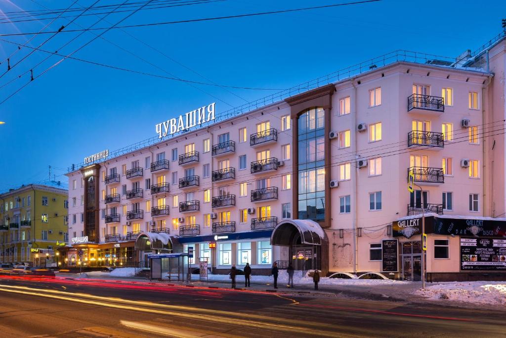 un grand bâtiment rose dans une rue de la ville la nuit dans l'établissement Chuvashia Hotel, à Tcheboksary