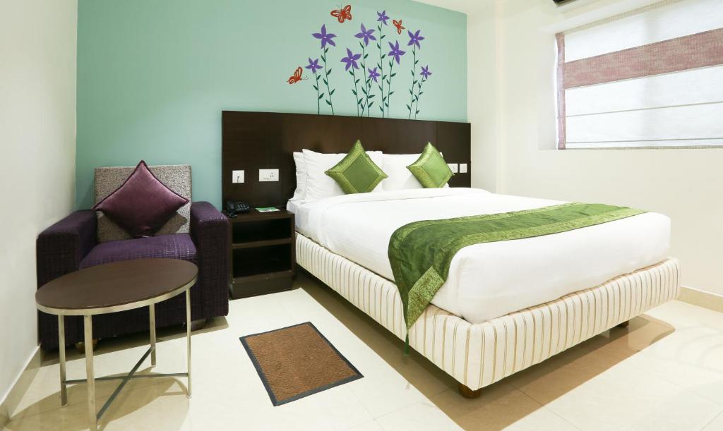 a bedroom with a bed and a chair and a table at Treebo Trend C Plaza in Vijayawāda