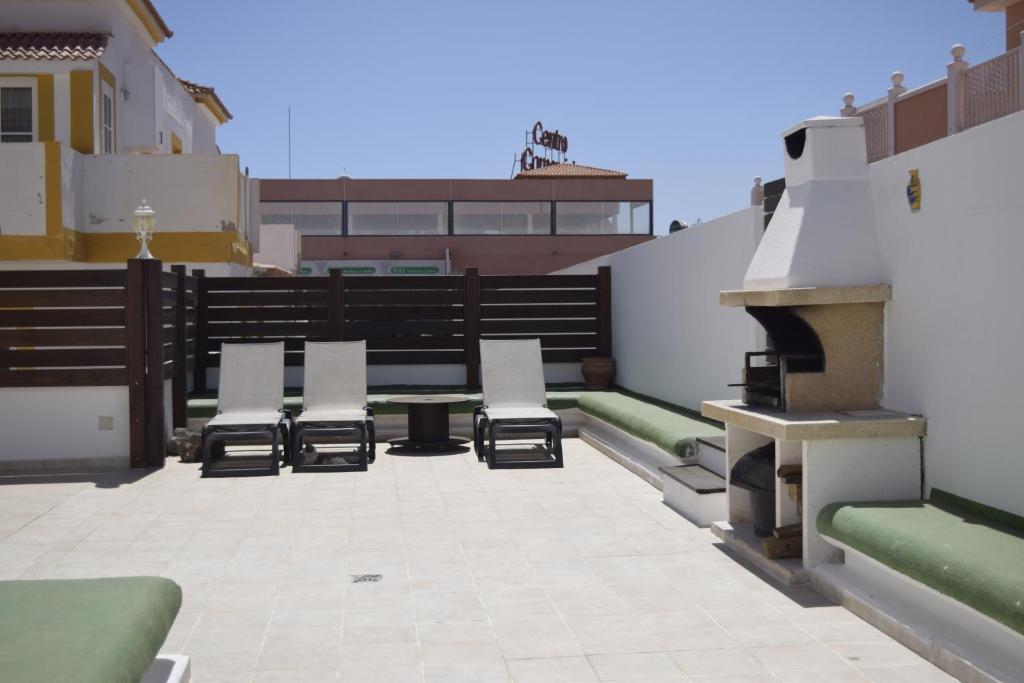 a patio with chairs and tables on a rooftop at Sol y Luna en Caleta de Fuste in Caleta De Fuste