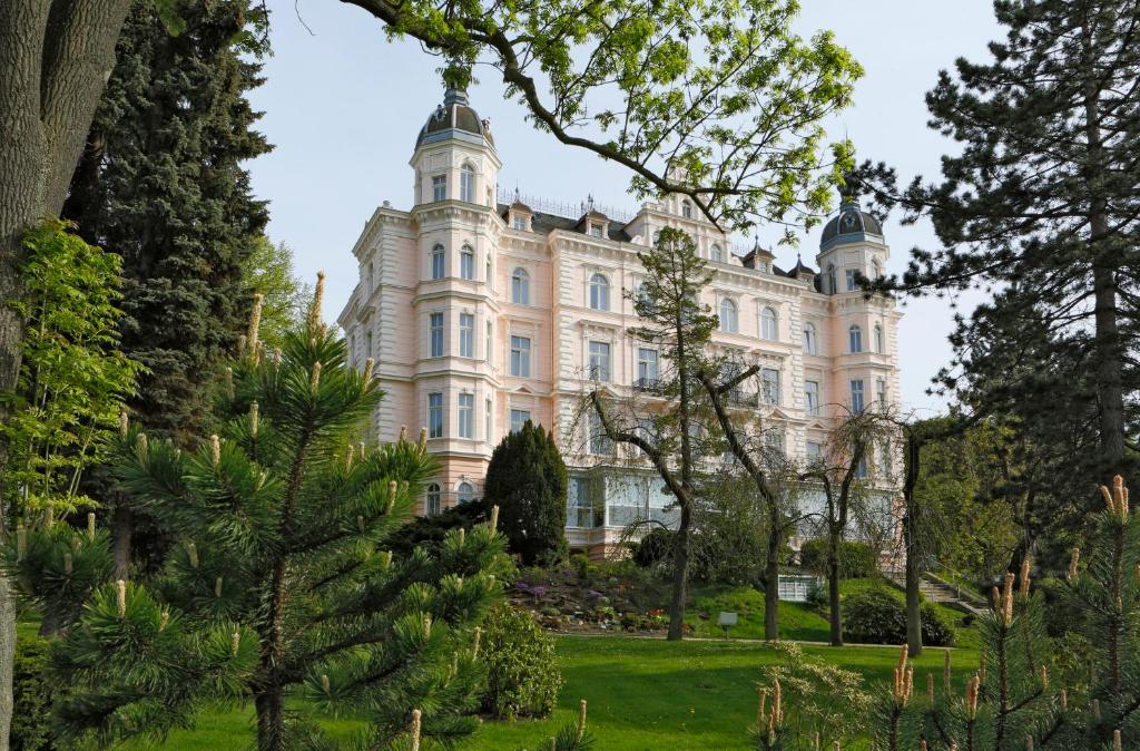una imagen de un edificio con árboles en primer plano en Bristol Palace, en Karlovy Vary