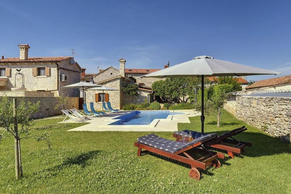 uma casa com guarda-sol e bancos e uma piscina em Villa Orbanici em Barban