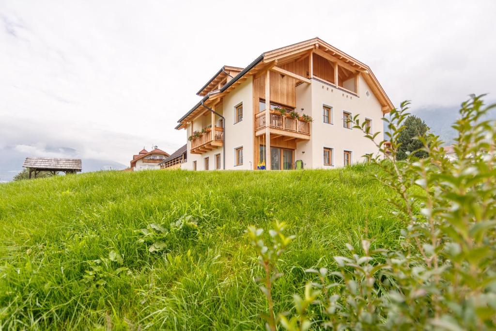 a house on top of a hill with green grass at Krebslechnerhof in Brunico