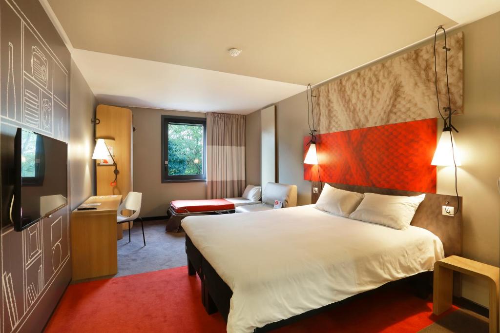 a bedroom with a large bed and a large window at ibis Le Mans Est Pontlieue in Le Mans