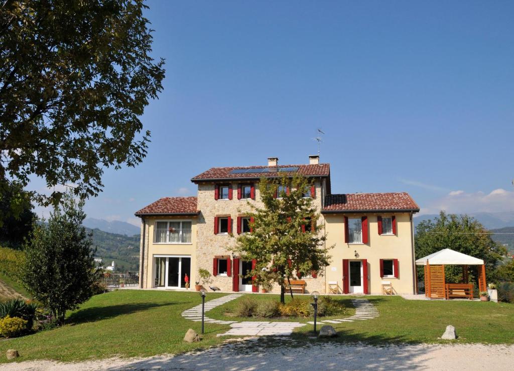 une grande maison avec un arbre en face dans l'établissement Agriturismo Lemire, à San Pietro di Feletto