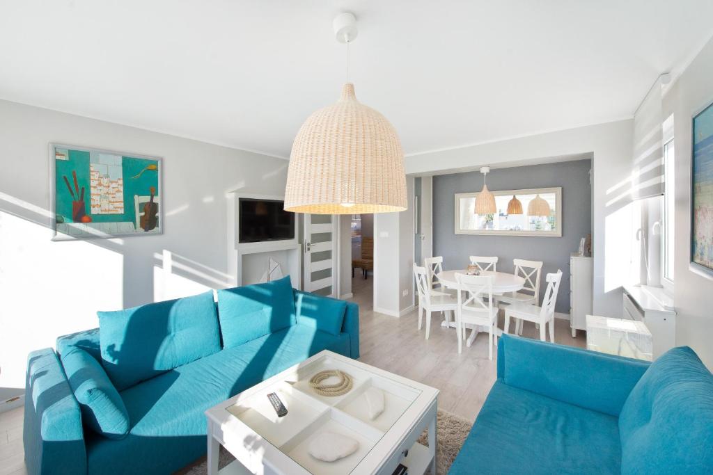 a living room with blue furniture and a dining room at Pomorskie Apartamenty Ceynowy 1 Deluxe in Sopot