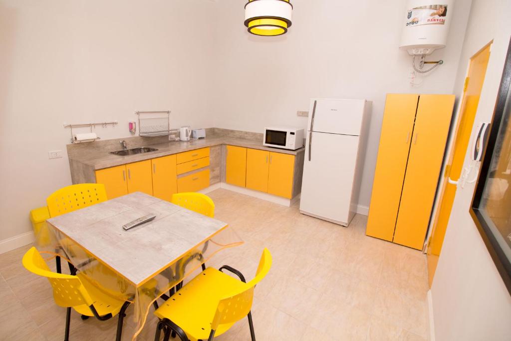 a kitchen with yellow cabinets and a table and yellow chairs at Colores Rio Cuarto in Río Cuarto