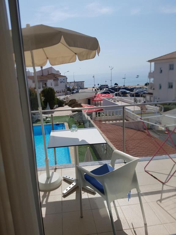 a balcony with a table and chairs and an umbrella at Casa Praia Mar in Salema