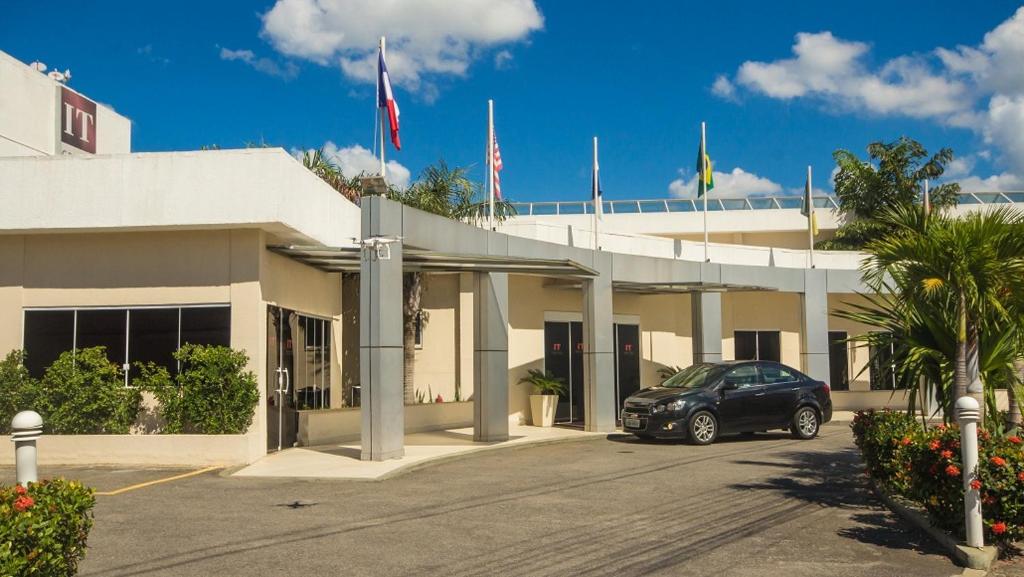 ein Fahrzeug, das vor einem Gebäude mit Flaggen parkt in der Unterkunft Grande Hotel Itaguaí in Itaguaí