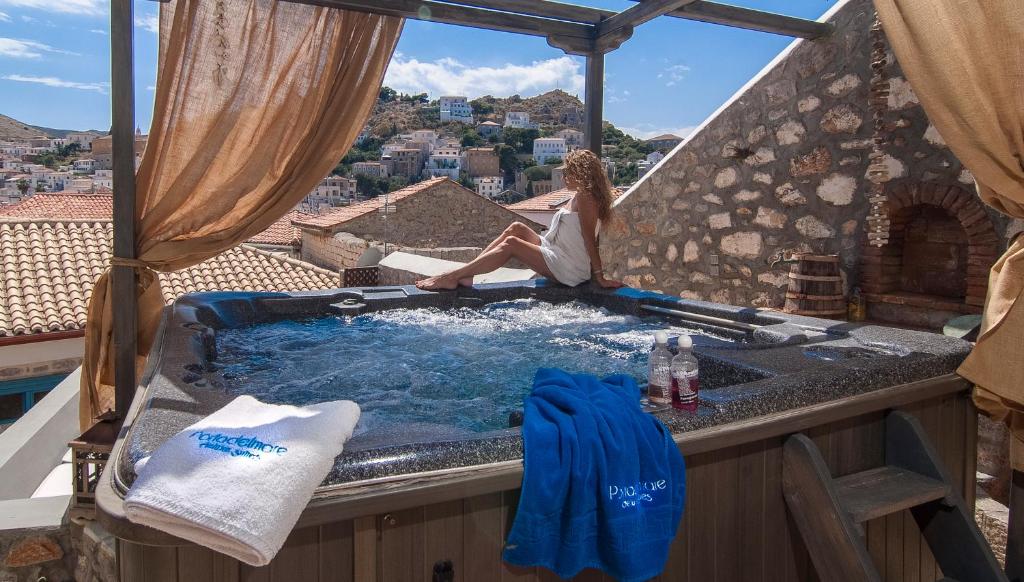 伊茲拉的住宿－PortaDelMare deluxe suites，坐在阳台上热水浴缸中的女人