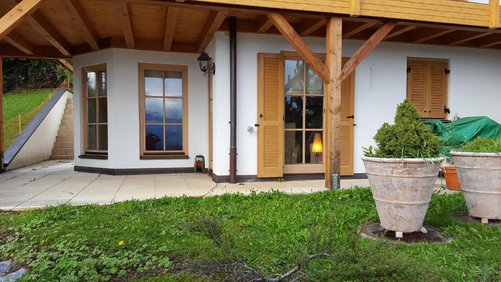 une maison avec une terrasse couverte et 2 grandes plantes en pot dans l'établissement Suite mit Parkplatz Gebertingen, à Gebertingen