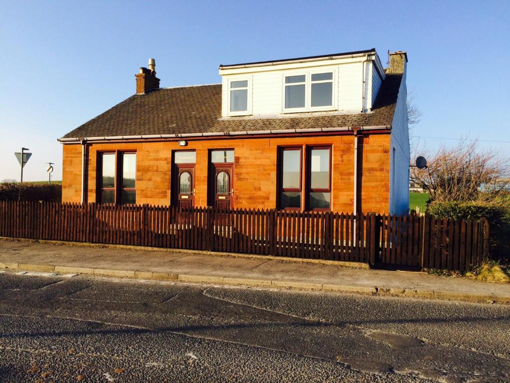 a house with a wooden fence in front of it at Ayrshire cottage in Kilmarnock