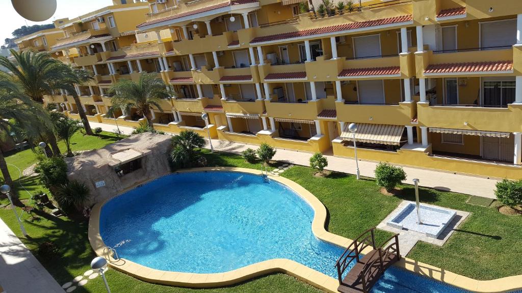 an apartment with a swimming pool in front of a building at Cascadas de la Marina in Denia
