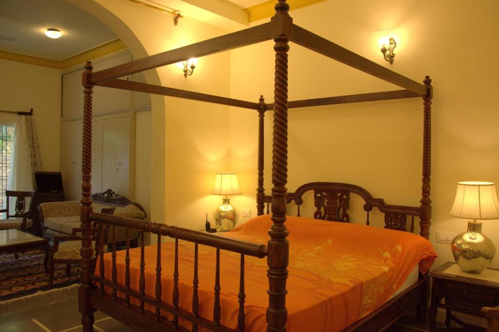 a bedroom with a four poster bed with orange sheets at Jai Villa Homestay in Udaipur
