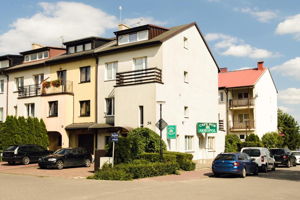 un gran edificio blanco con coches aparcados en un aparcamiento en Pokoje Gościnne Akropol, en Poznan