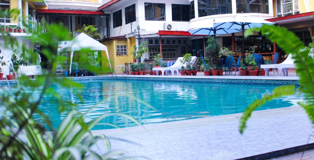 a swimming pool with chairs and umbrellas next to a building at Hotel Woodland Kathmandu in Kathmandu