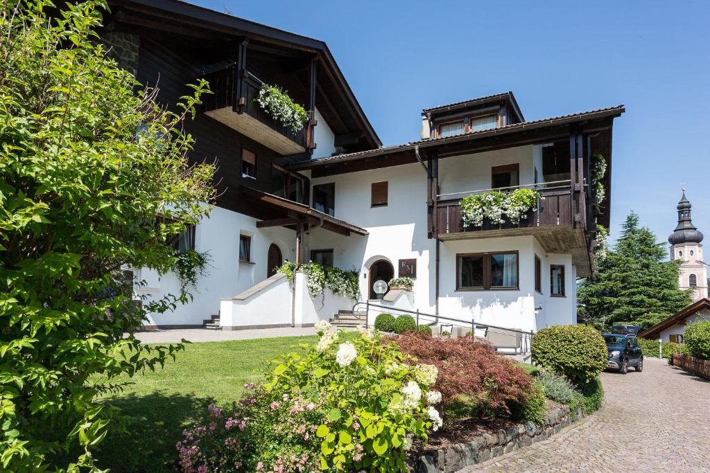 un grand bâtiment blanc avec des fleurs devant lui dans l'établissement Residence Mayr, à Castelrotto