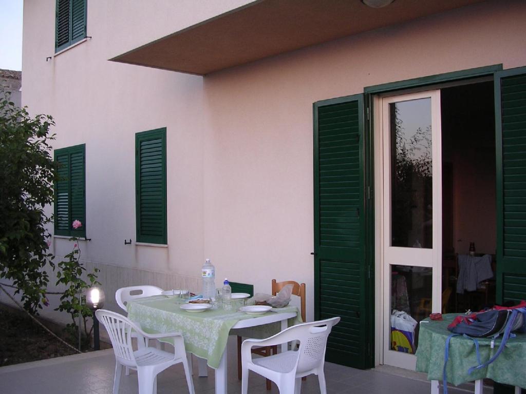 une table et des chaises sur une terrasse avec volets verts dans l'établissement Villetta Mare Valderice, à Valderice
