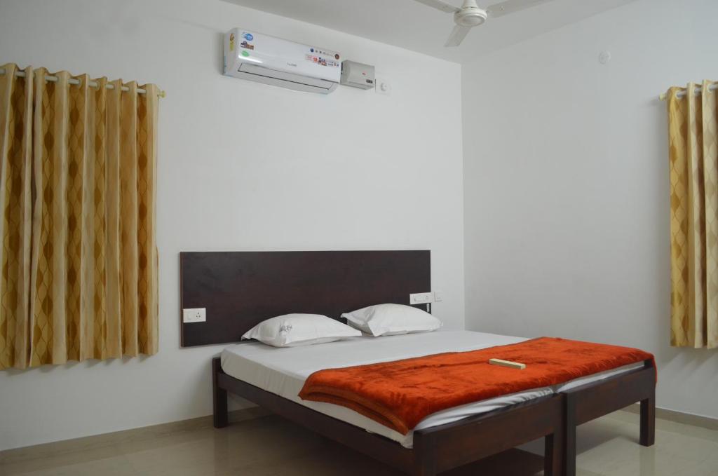 a bedroom with a bed with a orange blanket on it at Blackroots Serviced Apartments in Coimbatore