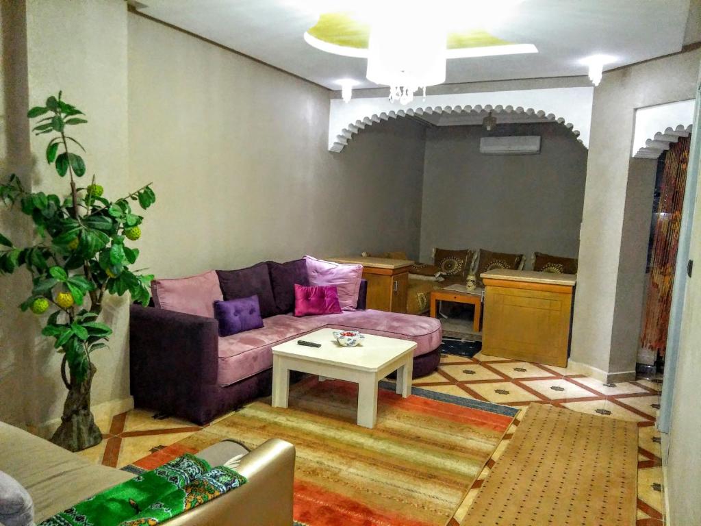 uma sala de estar com um sofá roxo e uma mesa em appartement Annakhil em Marrakech