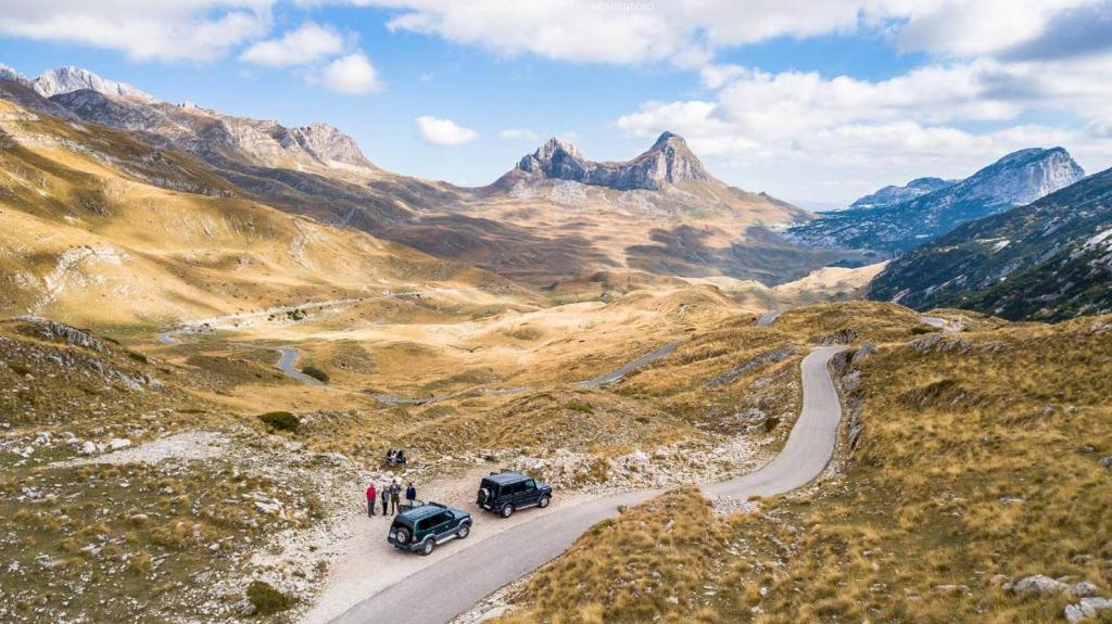dois carros descendo uma estrada em uma montanha em Summit Apartment em Žabljak