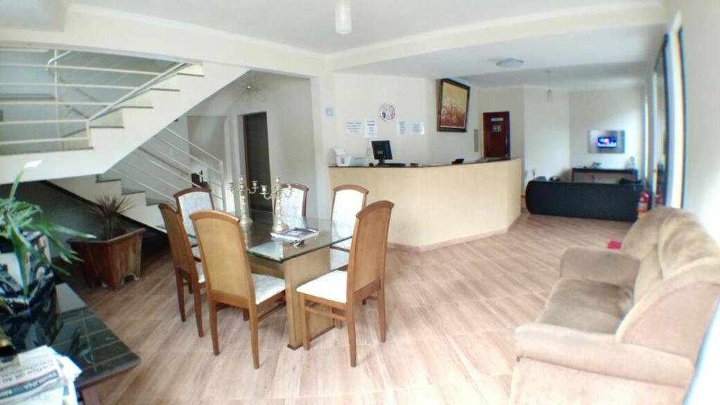 ein Wohnzimmer mit einem Tisch, Stühlen und einer Treppe in der Unterkunft Hotel Vitalle in Juiz de Fora